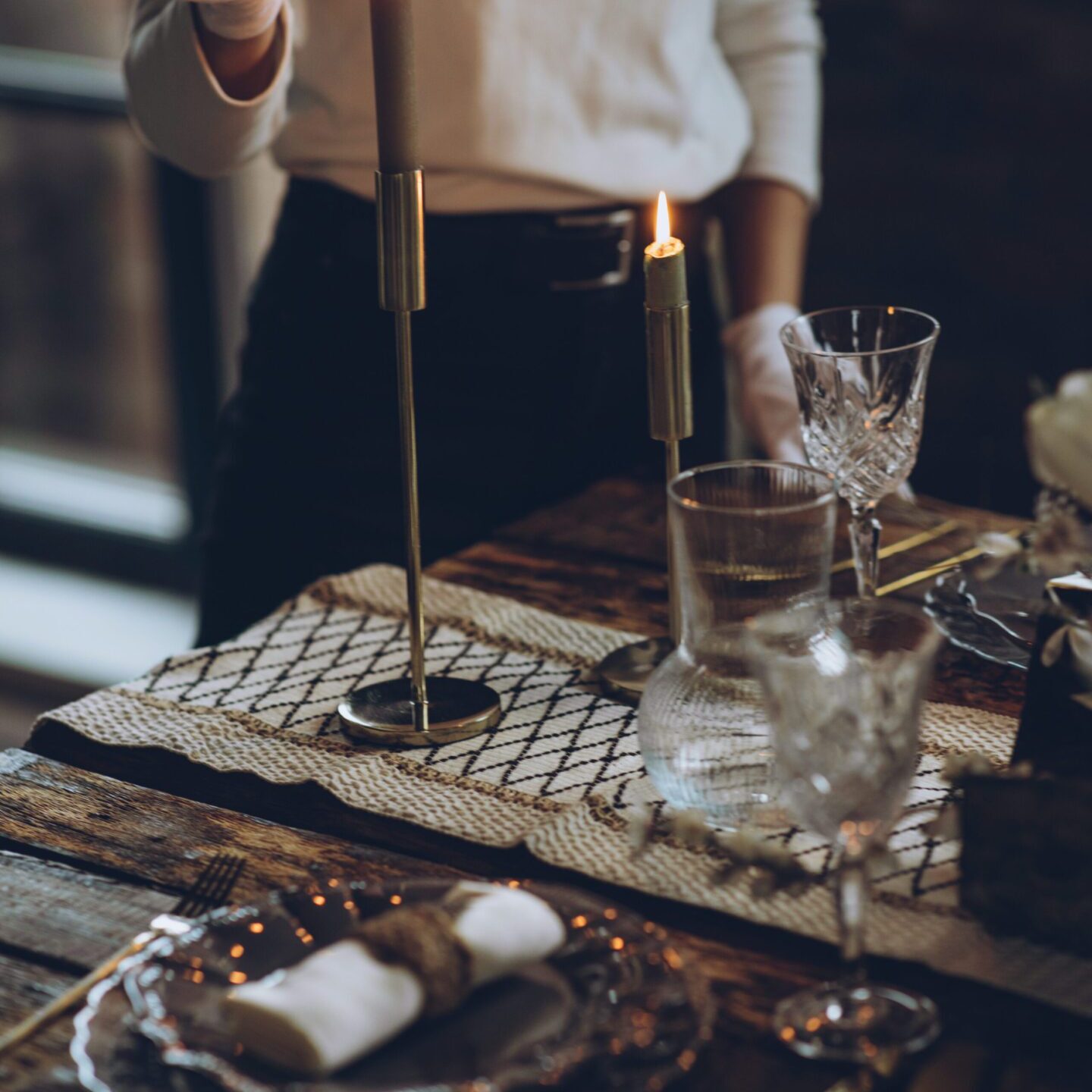 Person preparing a coffee drip setup with glasses and coffee beans on a wooden table.