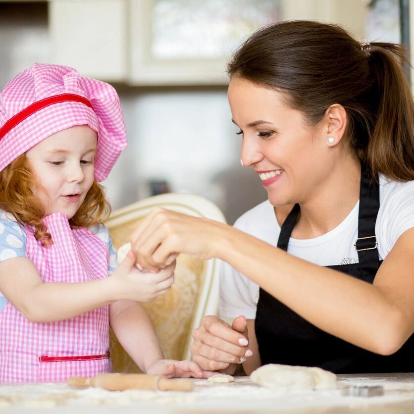 Mother and daughter baking together, sharing a joyful moment.