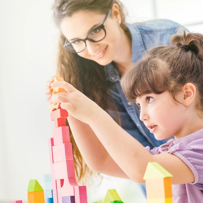 A woman and a girl building with colorful blocks together.